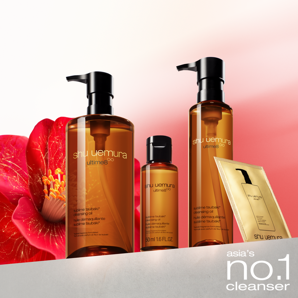 alt="Shu Uemura Ultime8∞ Sublime Tsubaki cleansing oil in three sizes — large, travel, and standard pump bottles — alongside a gold sachet sample, displayed next to a red tsubaki flower, promoted as Asia's number one cleanser."